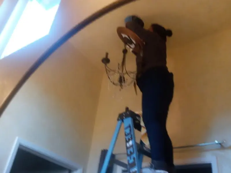 Electrician installing a chandelier in a Mountain House residence